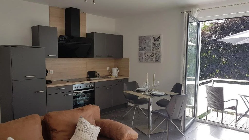 Moderne Küche in Grau und Holz im Cloud 7 II Apartment in Heinsberg-Oberbruch mit gedecktem Tisch und Blick ins Grüne